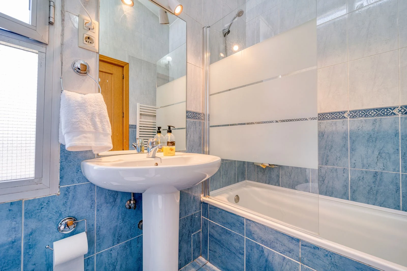 Compact bathroom with a fitted bath and blue tiles