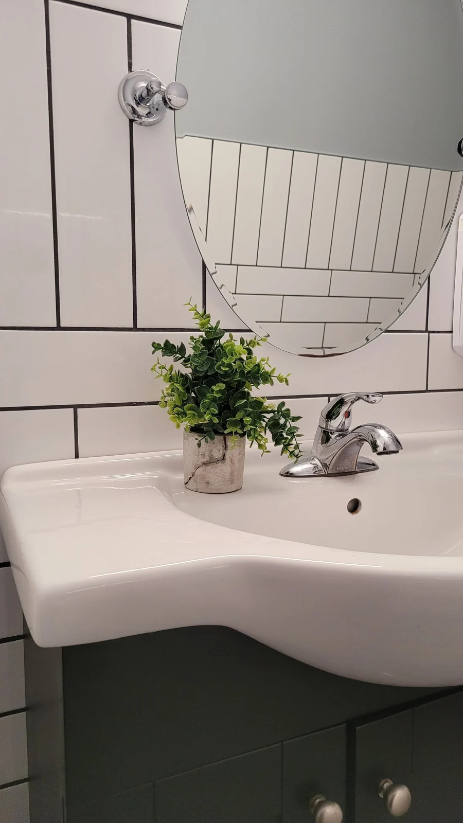 Stylish bathroom interior with sink, round mirror, and a touch of greenery