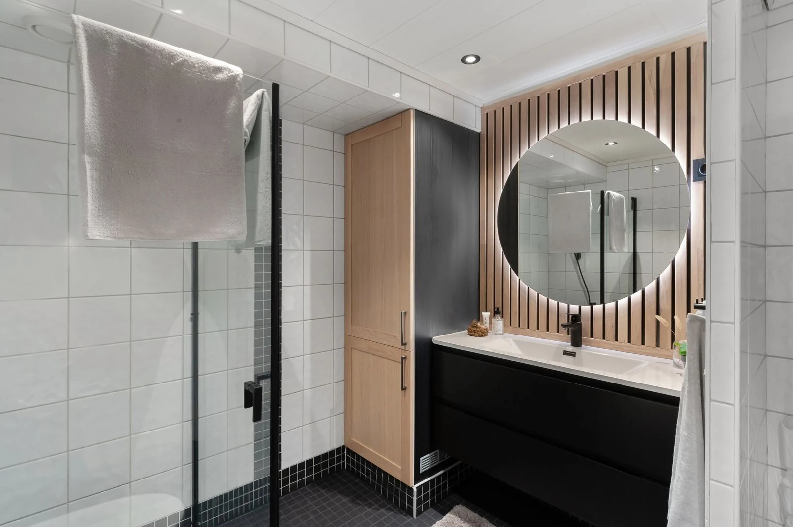 Sleek modern bathroom featuring an illuminated round mirror and contemporary fixtures