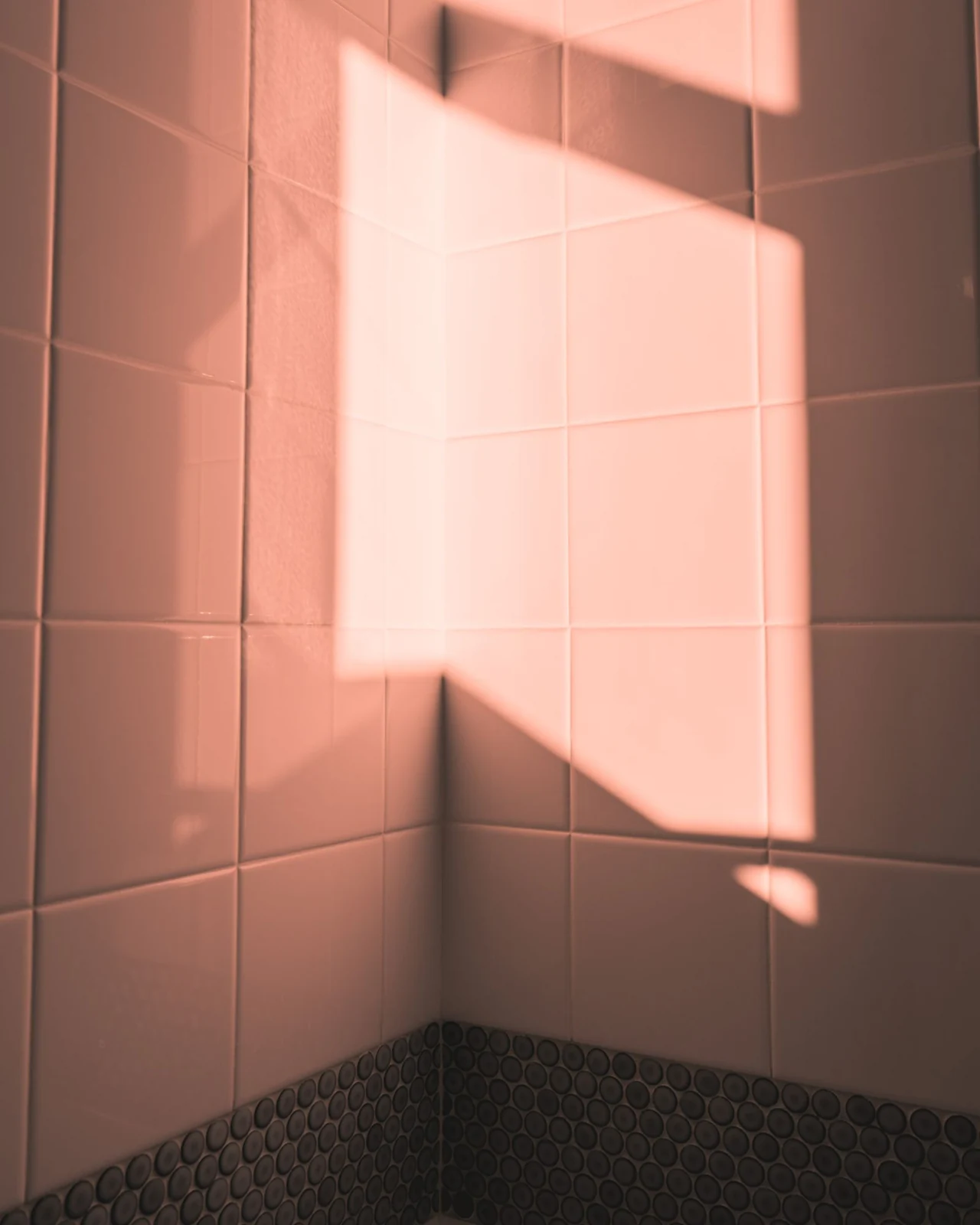 A serene minimalist shot showcasing sunlight reflecting on a tiled corner wall, creating a warm atmosphere