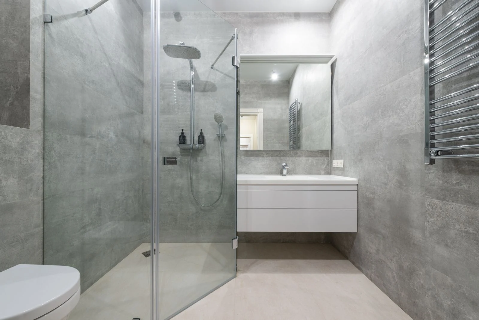 Creative design of bathroom with toilet bowl and washbasin under mirror against rack on tiled wall in house