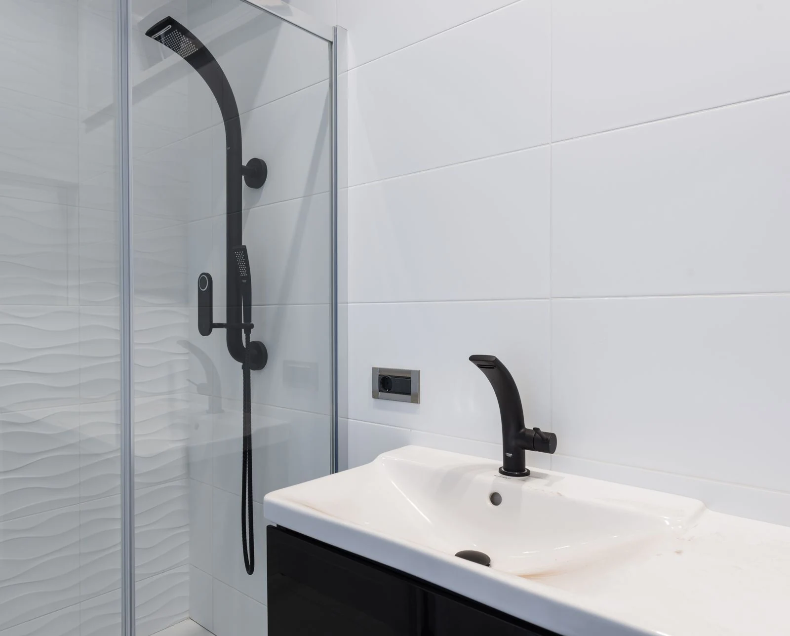 Modern minimalist style interior design of bathroom with white tiled walls and washbasin and black faucet and shower unit with glass partition